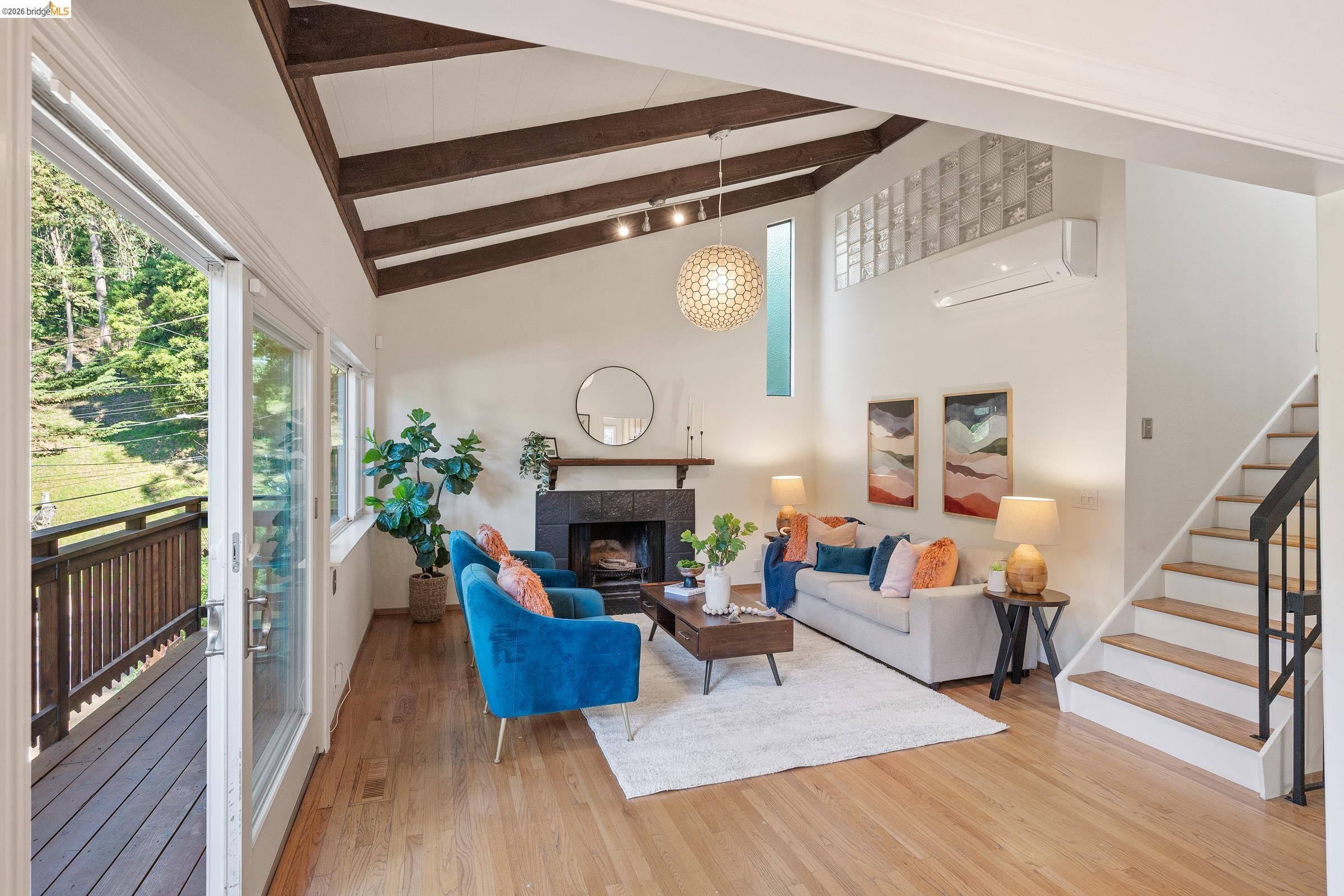 6600 Heather Ridge Way Oakland, CA 94611 - Photo 6 of 66 Vaulted ceilings with exposed beams, fireplace with dark tile surround, hardwood flooring, and sliding glass doors to outdoor decking