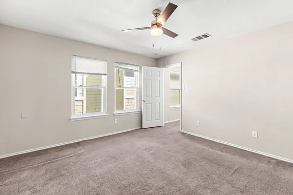 an empty room with windows and fan