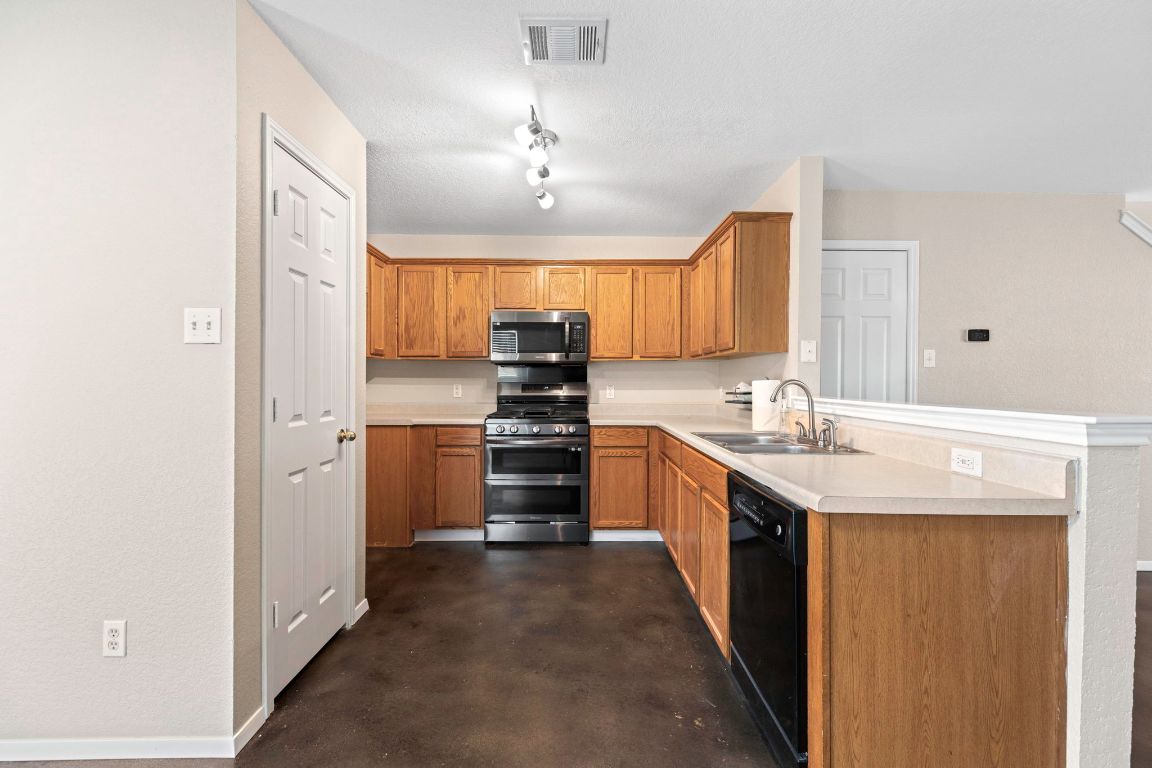 284 Michaelis Road Kyle, TX 78640 - Photo 7 of 20 a kitchen with stainless steel appliances granite countertop a sink stove and refrigerator