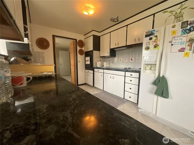 a kitchen with stainless steel appliances granite countertop a refrigerator a sink and white cabinets