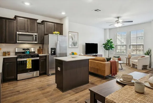a kitchen with kitchen island granite countertop a sink dishwasher stove and refrigerator with wooden floor