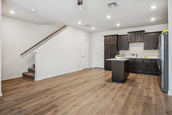 an open kitchen with kitchen island a sink wooden floor and stainless steel appliances