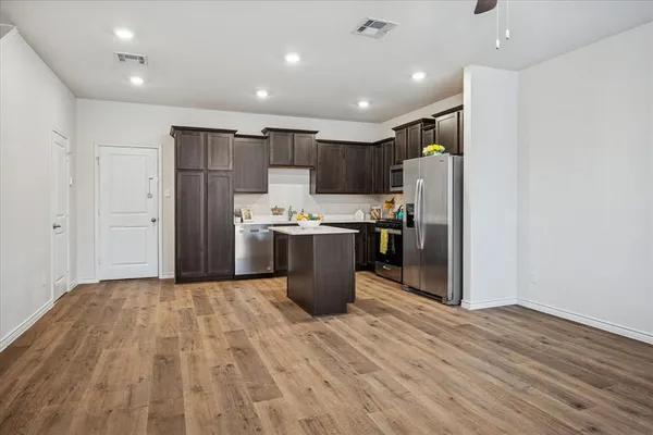 a kitchen with stainless steel appliances a refrigerator and a wooden floor