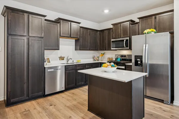 a kitchen with kitchen island a refrigerator sink and wooden cabinets