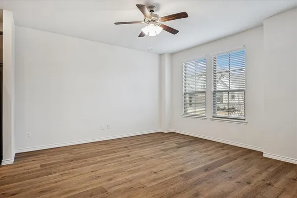 a view of an empty room with window and wooden floor