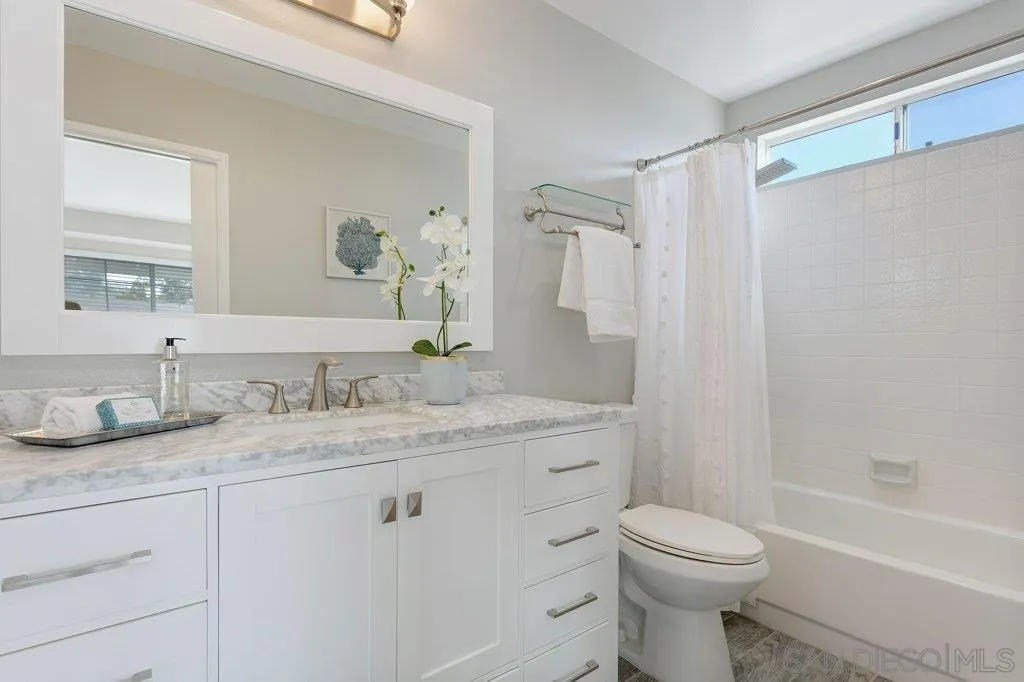 2725 Glasgow Drive Carlsbad, CA 92010 - Photo 19 of 29 a bathroom with a granite countertop sink toilet a large mirror a shower and a window
