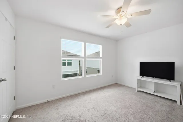 an empty room with windows and fan