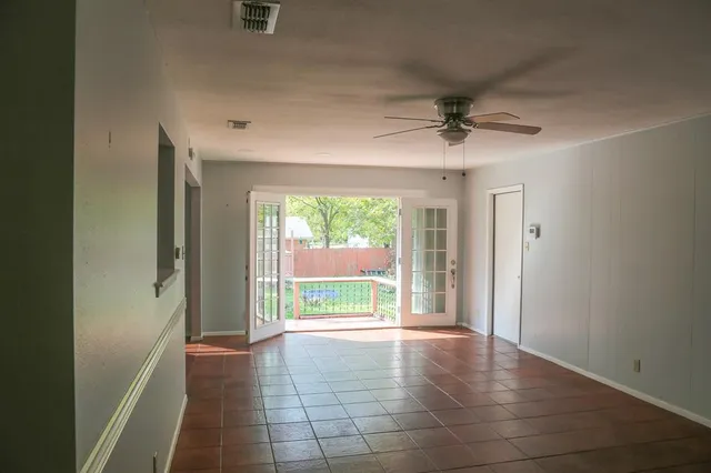 an empty room with windows and a ceiling fan