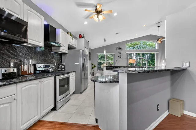 a kitchen with kitchen island granite countertop a sink window and stainless steel appliances