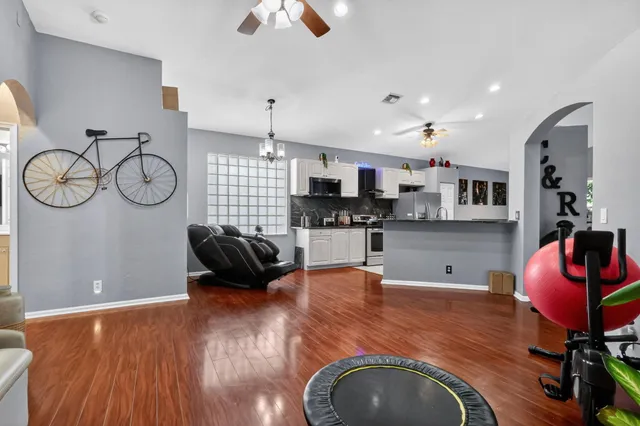 a kitchen with stainless steel appliances granite countertop a stove top oven a sink a dining table and chairs with wooden floor