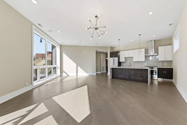a view of a kitchen with kitchen island stainless steel appliances wooden floor dining table and chairs