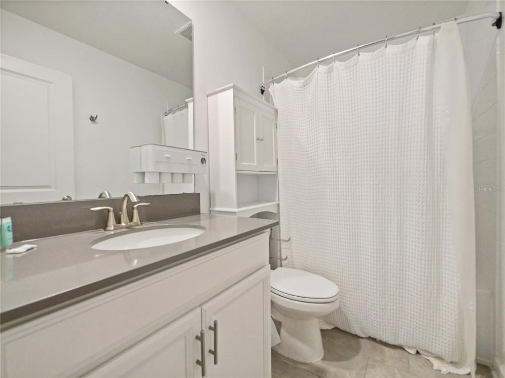 9084 Sommerset Hills Drive Davenport, FL 33896 - Photo 25 of 63 a bathroom with a granite countertop sink toilet and a mirror