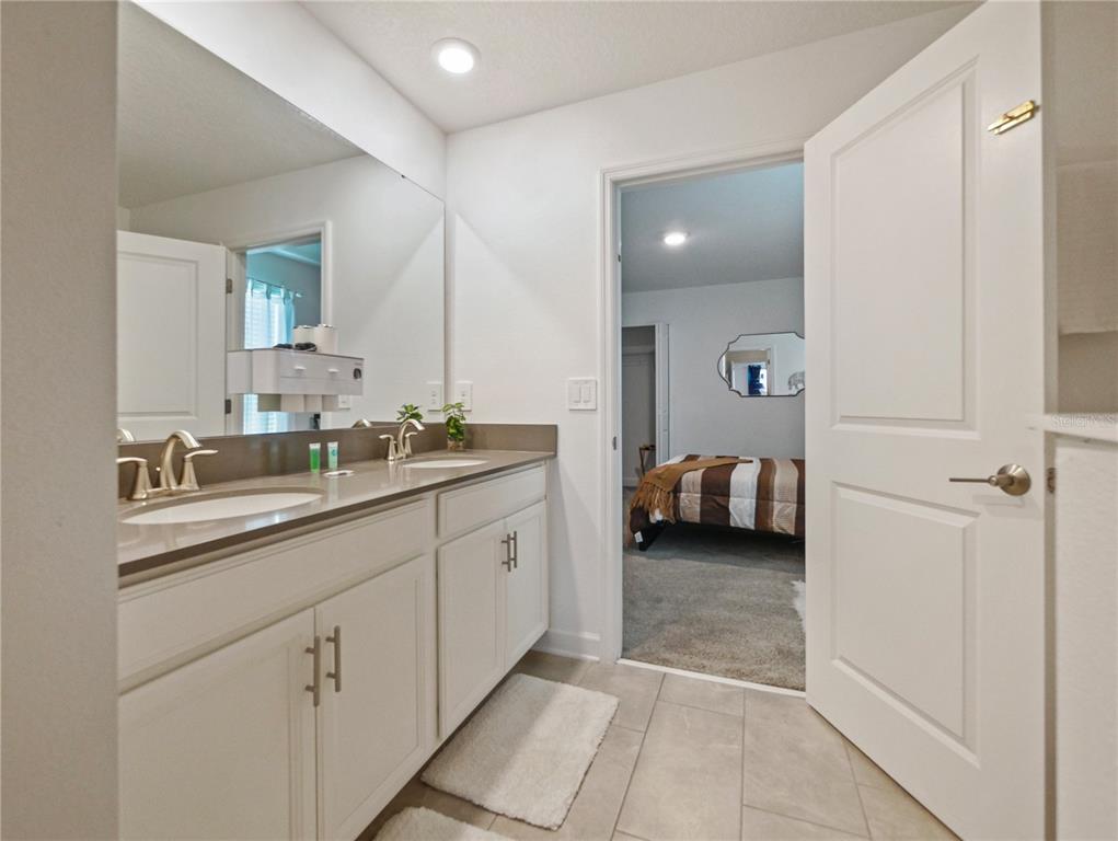 9084 Sommerset Hills Drive Davenport, FL 33896 - Photo 34 of 63 a en suite bathroom with a double vanity sink and a mirror