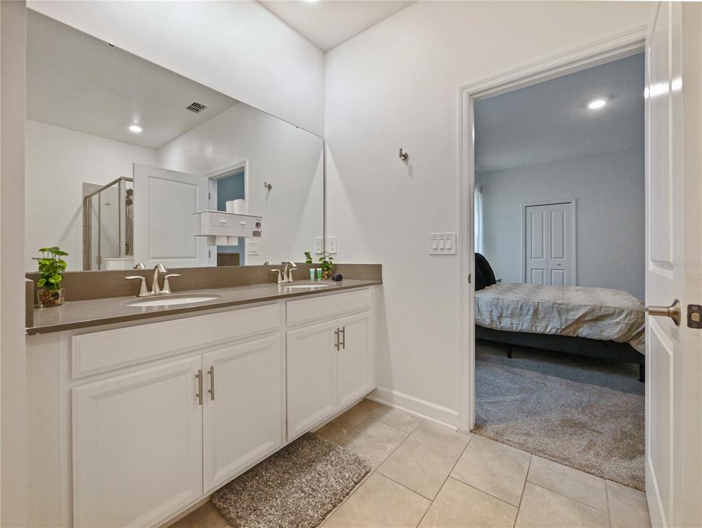 9084 Sommerset Hills Drive Davenport, FL 33896 - Photo 45 of 63 a en suite bathroom with a double vanity sink and a mirror