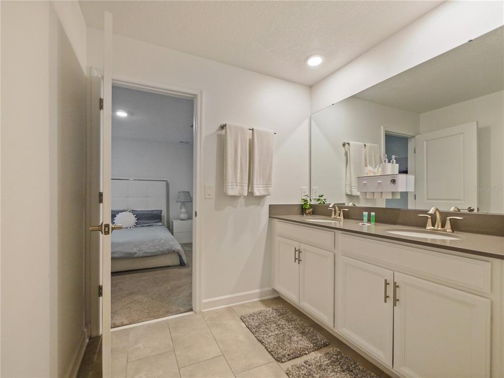 9084 Sommerset Hills Drive Davenport, FL 33896 - Photo 51 of 63 a bathroom with a double vanity sink a mirror and a bathtub