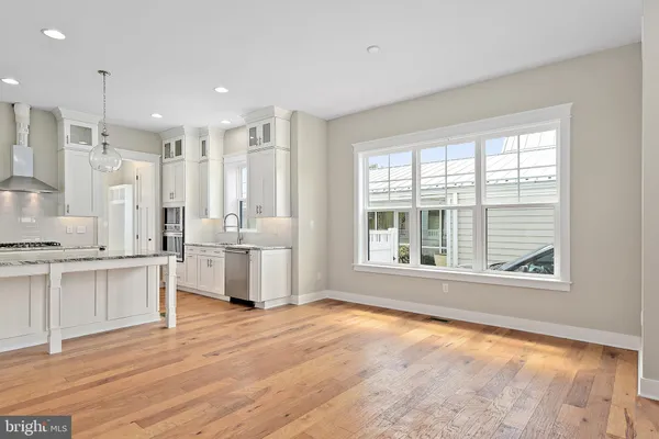 a large white kitchen with granite countertop a large counter top appliances and cabinets