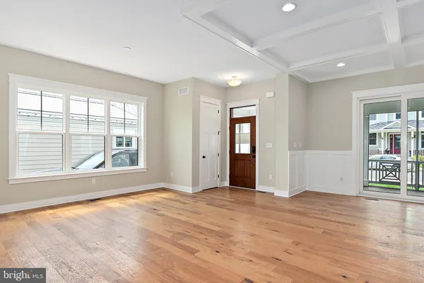 a view of an empty room with window and wooden floor