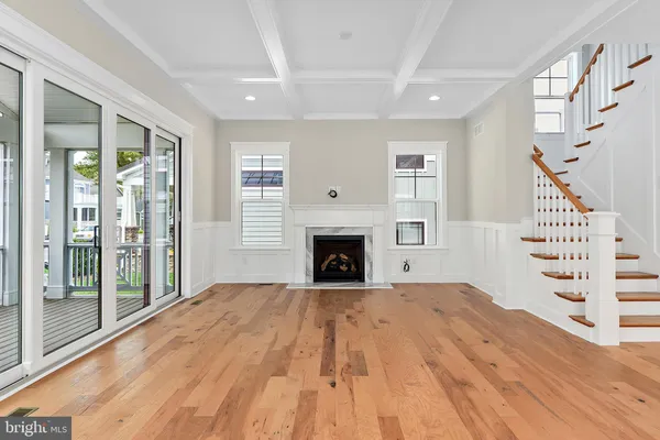a view of an empty room with wooden floor fireplace and a window