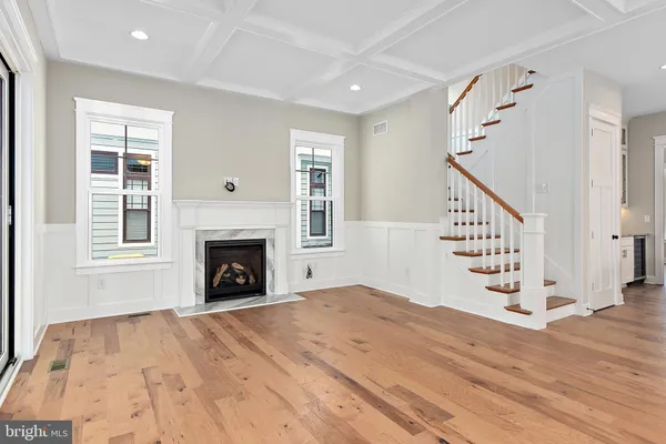 a view of an empty room with wooden floor fireplace and windows