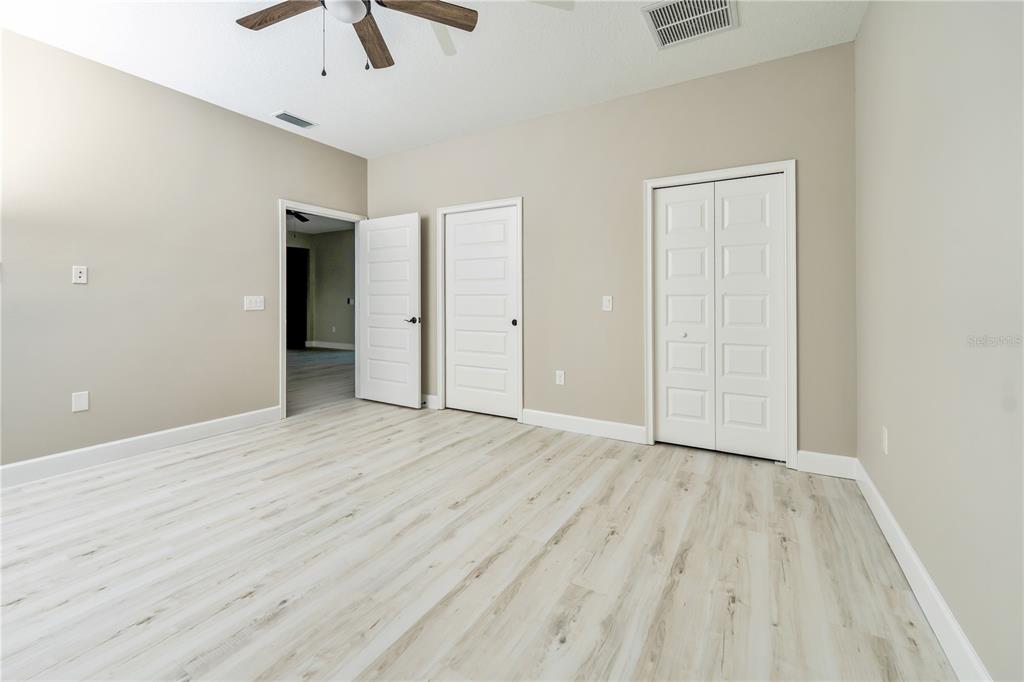 1011 Johnston Road Southeast Palm Bay, FL 32909 - Photo 22 of 47 an empty room with wooden floor ceiling fan and windows