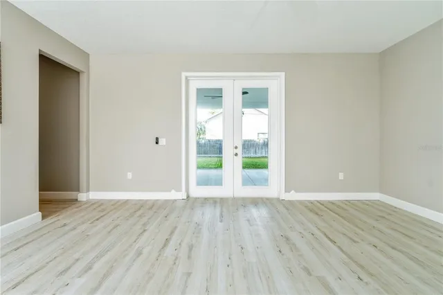 a view of an empty room with a window and wooden floor