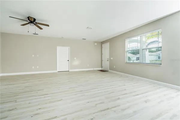 a view of an empty room with a window and wooden floor
