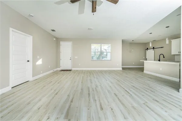 an empty room with wooden floor cabinet and windows