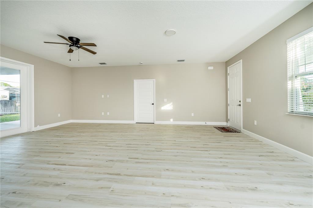 1011 Johnston Road Southeast Palm Bay, FL 32909 - Photo 7 of 47 an empty room with wooden floor a ceiling fan and windows
