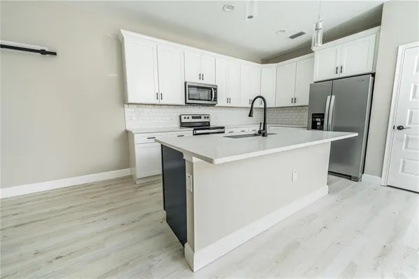 a kitchen with stainless steel appliances granite countertop a refrigerator sink and white cabinets