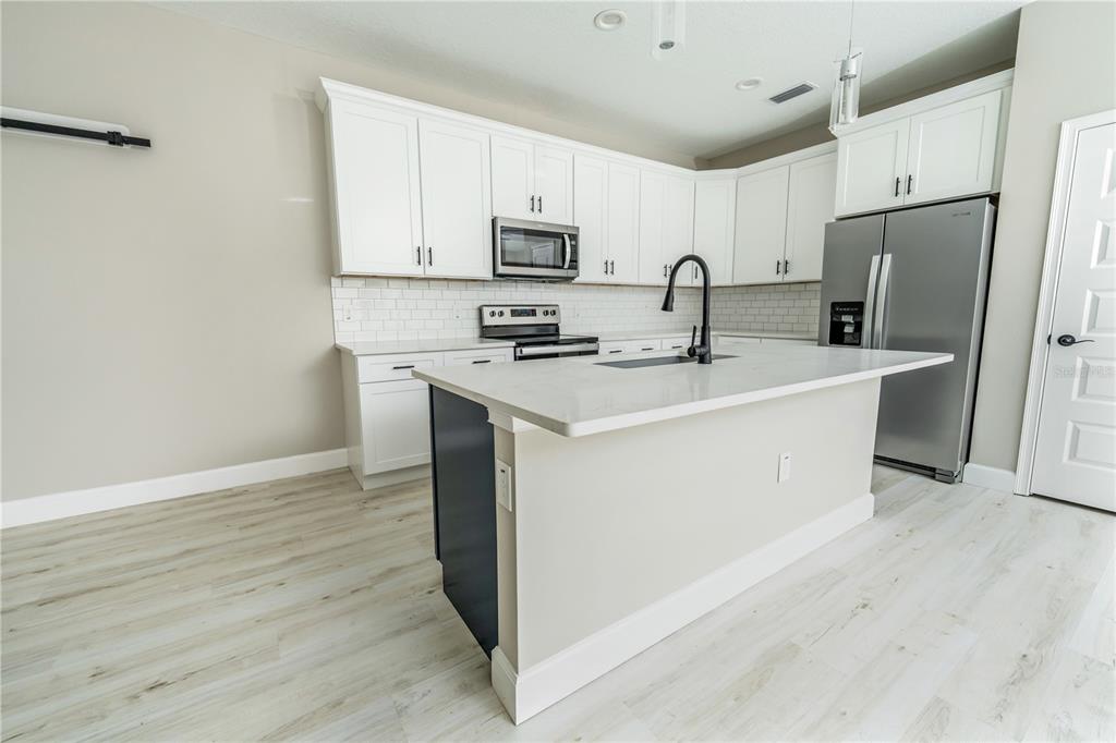 1011 Johnston Road Southeast Palm Bay, FL 32909 - Photo 8 of 47 a kitchen with stainless steel appliances granite countertop a refrigerator sink and white cabinets