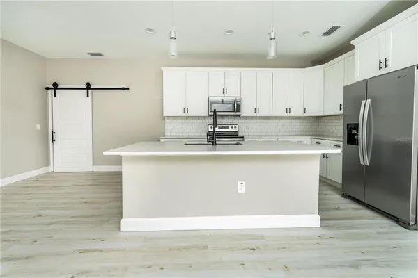 a view of kitchen with stainless steel appliances granite countertop a stove a refrigerator a sink dishwasher and a refrigerator with wooden floor