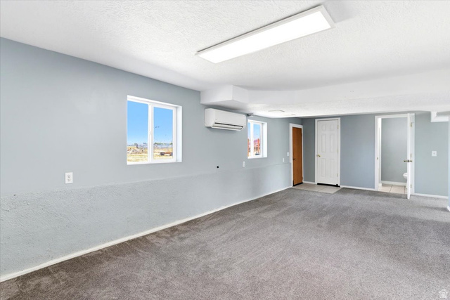 1613 Sunset Road Lake Point, UT 84074 - Photo 18 of 33 Spacious room featuring light gray walls, textured lower wall paneling, and dark gray carpeting