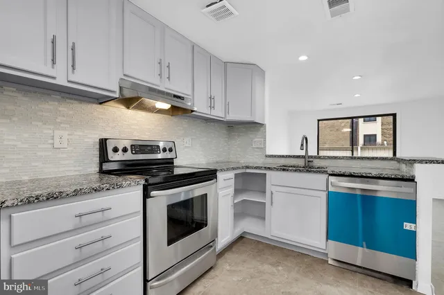 a kitchen with granite countertop cabinets stainless steel appliances and a sink