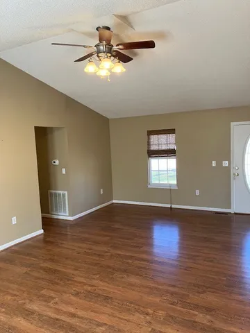 a view of an empty room with window and wooden floor