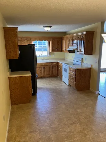 a living room with stainless steel appliances kitchen island granite countertop a refrigerator and a stove top oven