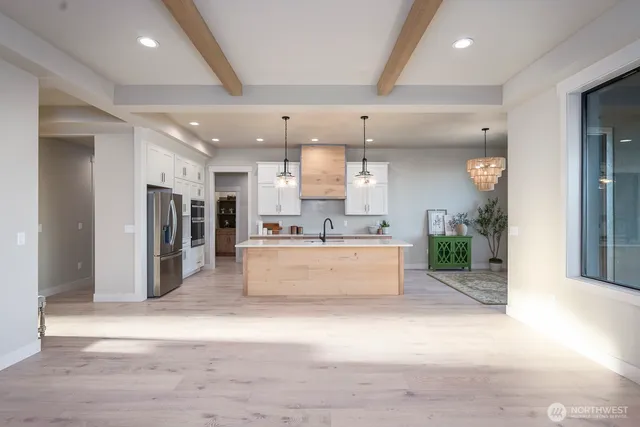 a large white kitchen with a large window and stainless steel appliances