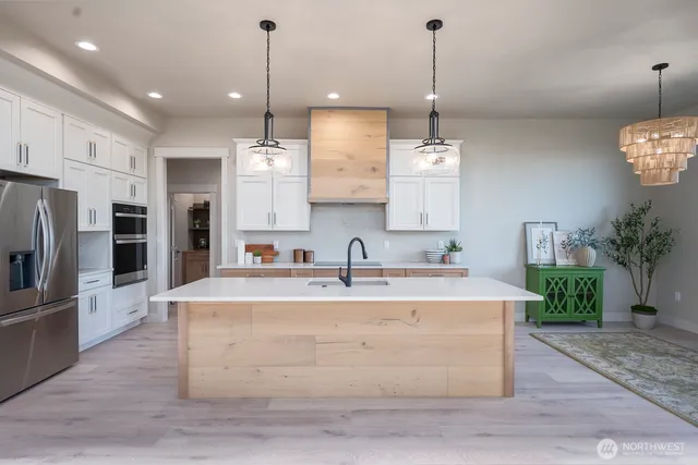a large kitchen with kitchen island white cabinets and stainless steel appliances