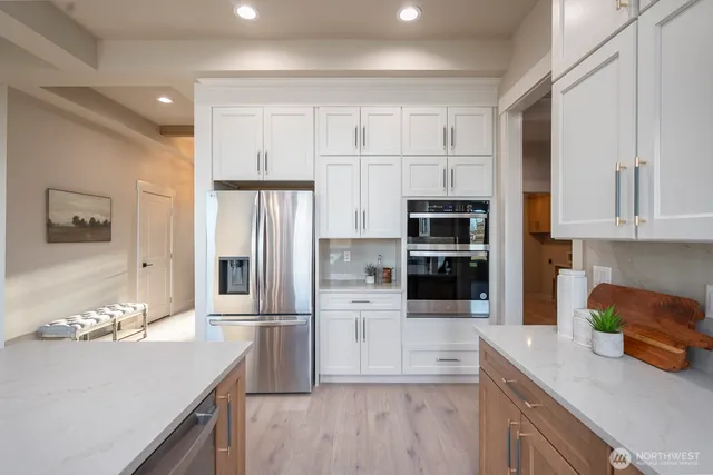 a large white kitchen with center island and stainless steel appliances