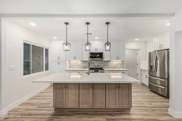 a large white kitchen with kitchen island white cabinets and stainless steel appliances