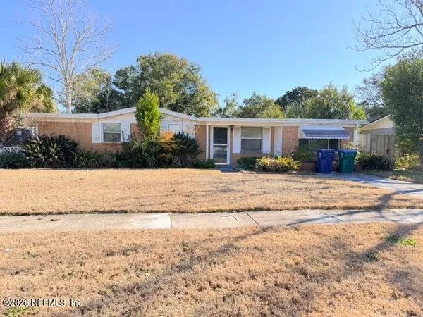 a view of house with yard and a large tree in front it