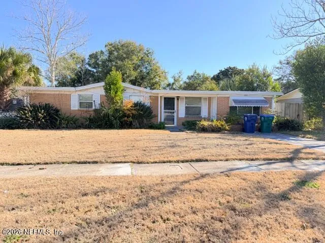 a view of house with yard and a large tree in front it