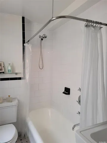 a white bath tub sitting next to a white toilet and vanity