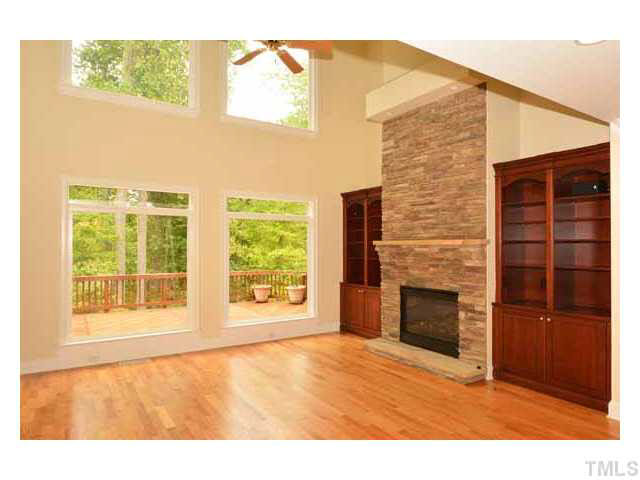 7108 Rippling Stone Lane Raleigh, NC 27612 - Photo 3 of 25 The picture windows frame the lush woods which surround the yard. The two story stacked stone fireplace with gas logs and custom bookshelves are wonderful features. The REAL hardwood floors have been freshly re-finished and look amazing!