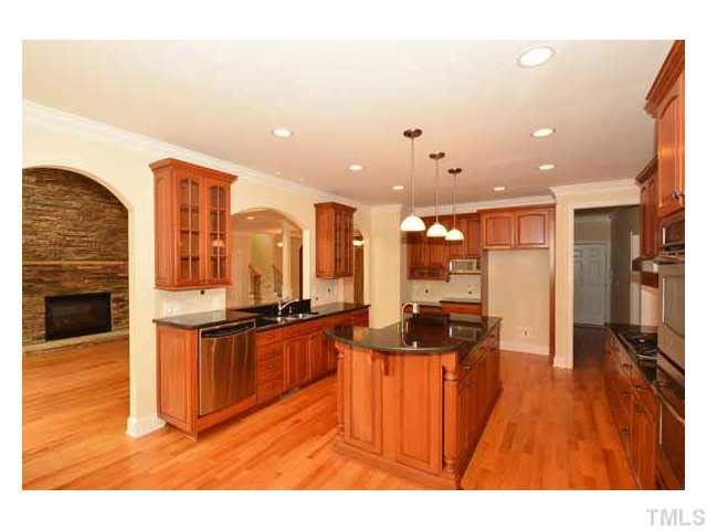 7108 Rippling Stone Lane Raleigh, NC 27612 - Photo 7 of 25 The beauty of this kitchen is framed by the three arched openings so it is nice and open! The island is nicely trimmed with raised panels and bookcases at the other end.