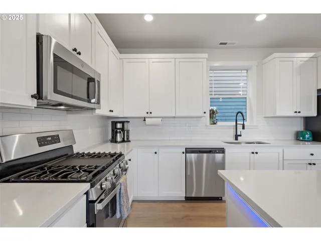 a kitchen with stainless steel appliances granite countertop a stove a sink and a microwave