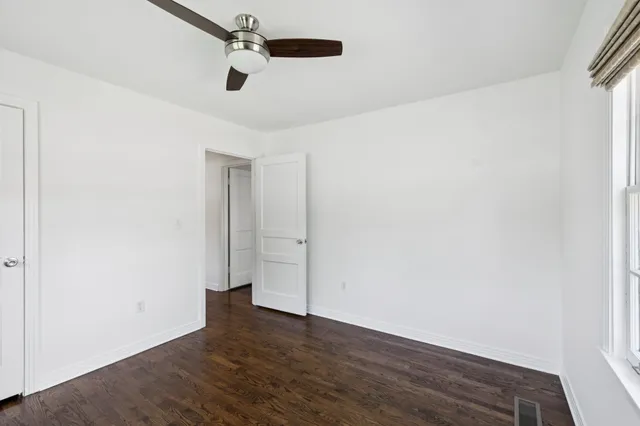 an empty room with wooden floor ceiling fan