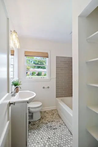 a bathroom with a granite countertop sink a toilet a mirror and shower