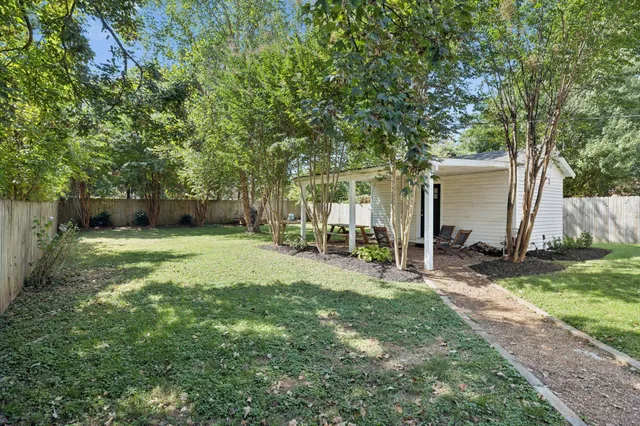 a view of a backyard with table and chairs and a large tree