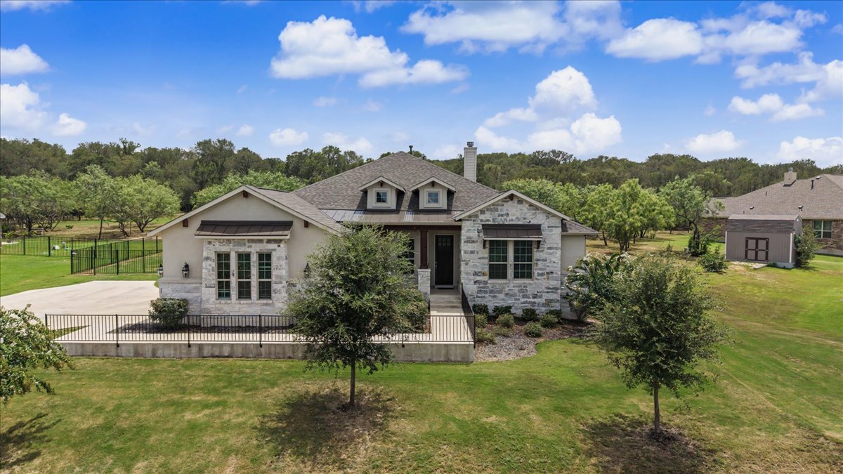 320 Raptor Beak Way Cedar Creek, TX 78612 - Photo 2 of 40 A well-maintained single-story residence with a stone facade and ample green space awaits.