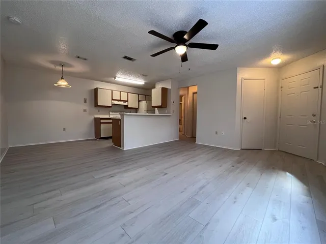 an empty room with wooden floor and a ceiling fan